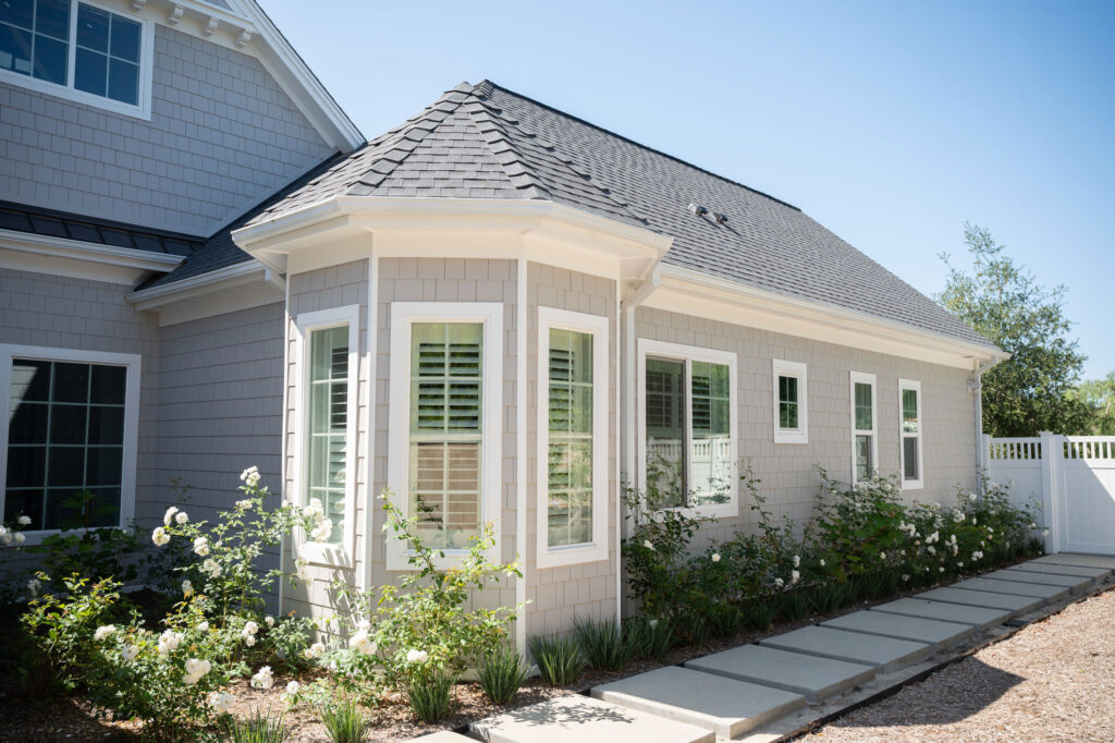 A modern looking house featuring stone walkway, small pebble pad, and immaculate landscaping