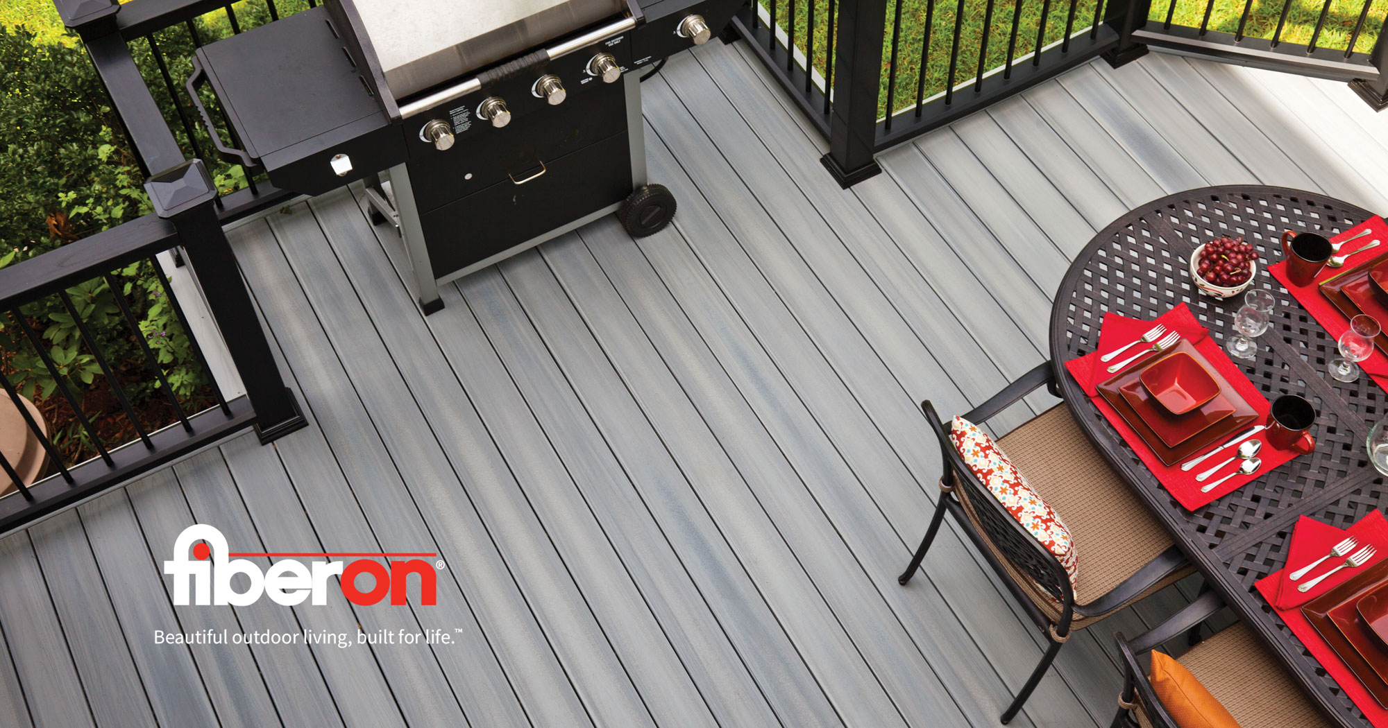 A Fiberon graphic - looking down on a designed deck featuring gray deck, black railing, and red accent furniture.