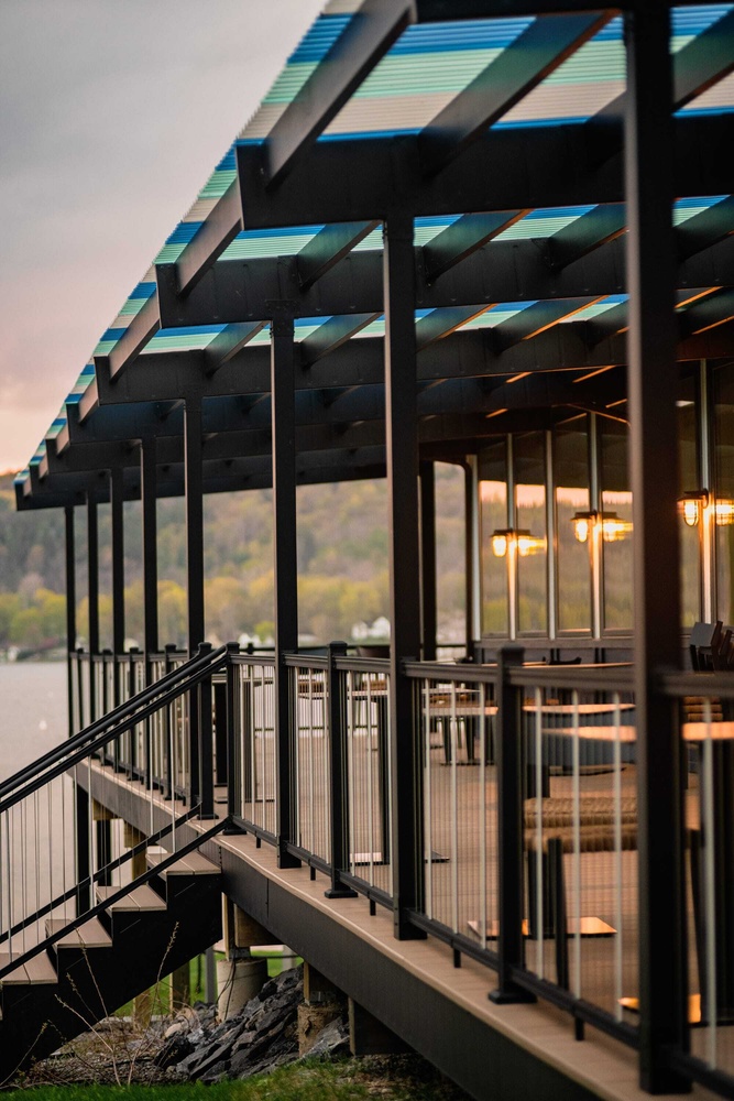 A modern looking restaurant deck featuring black railing and framing and accent brown deck boards.