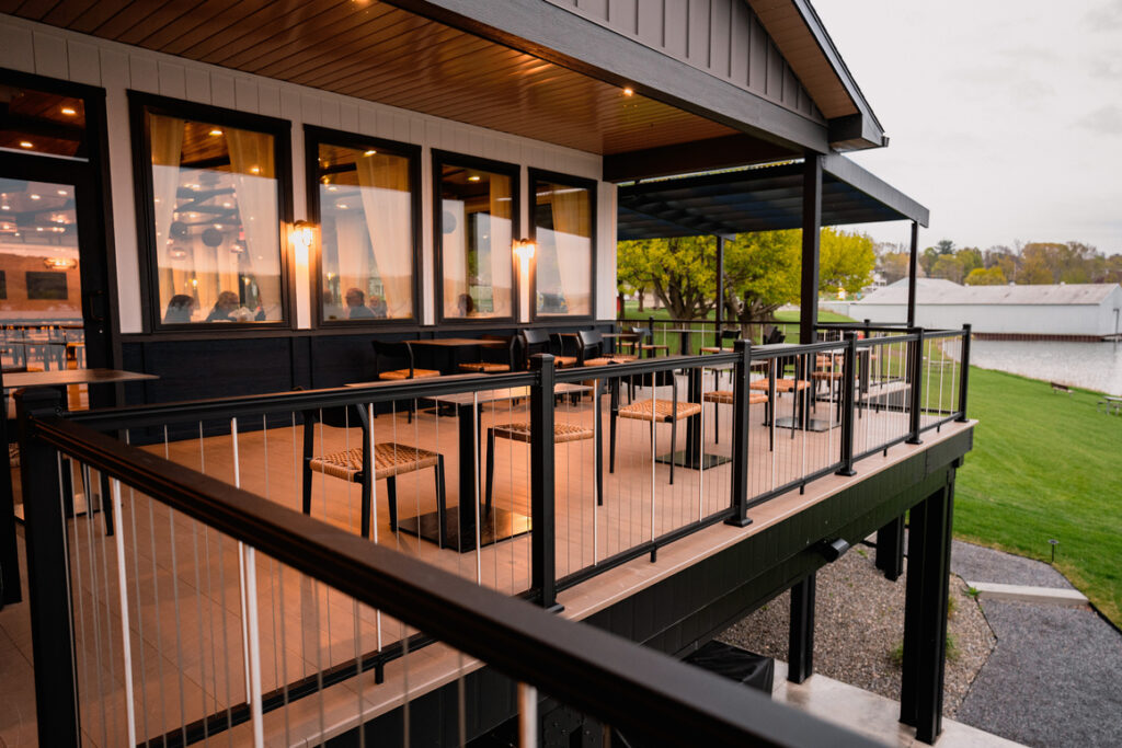 The back patio off a fancy restaurant featuring black railing and brown decking.