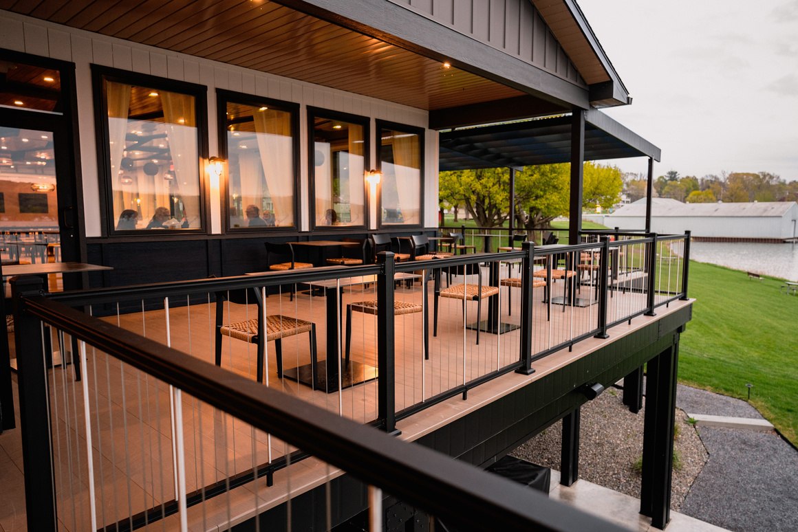 The back patio off a fancy restaurant featuring black railing and brown decking.