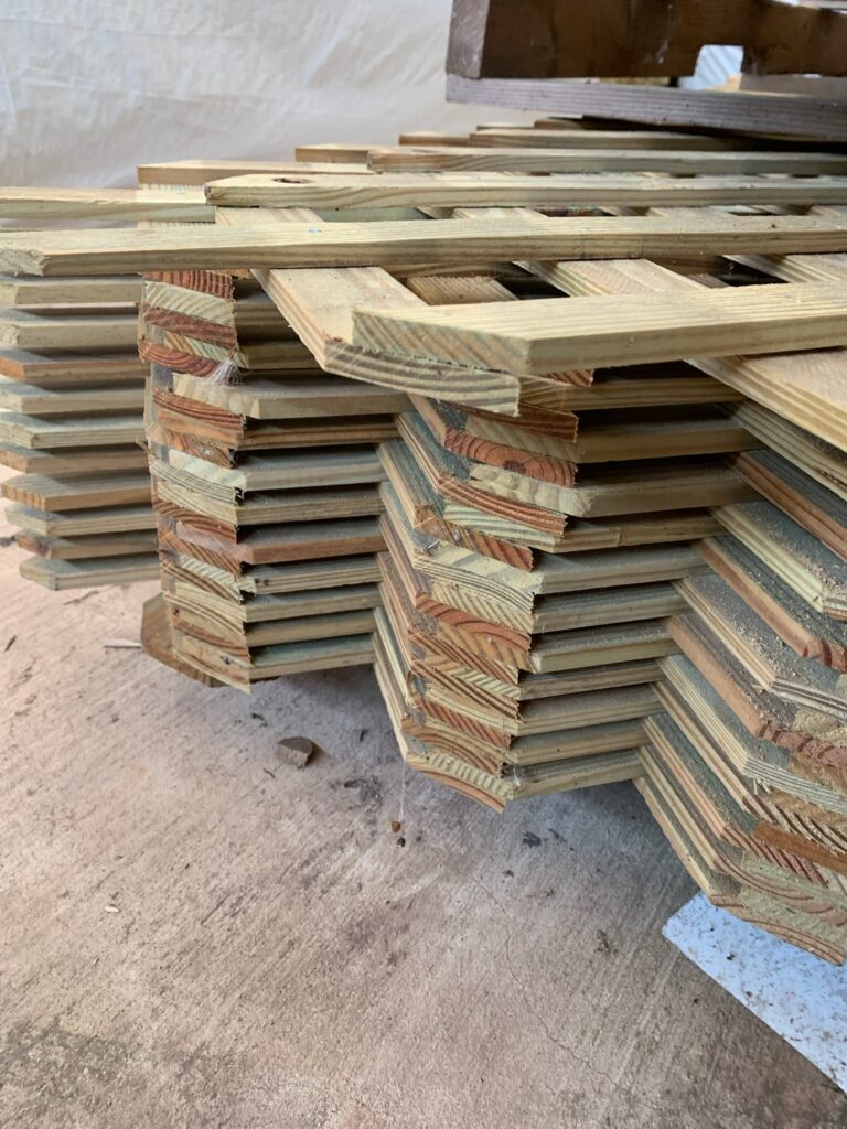 A stack of wooden lattice privacy walls. It is made out of Yellawood branded lumber.