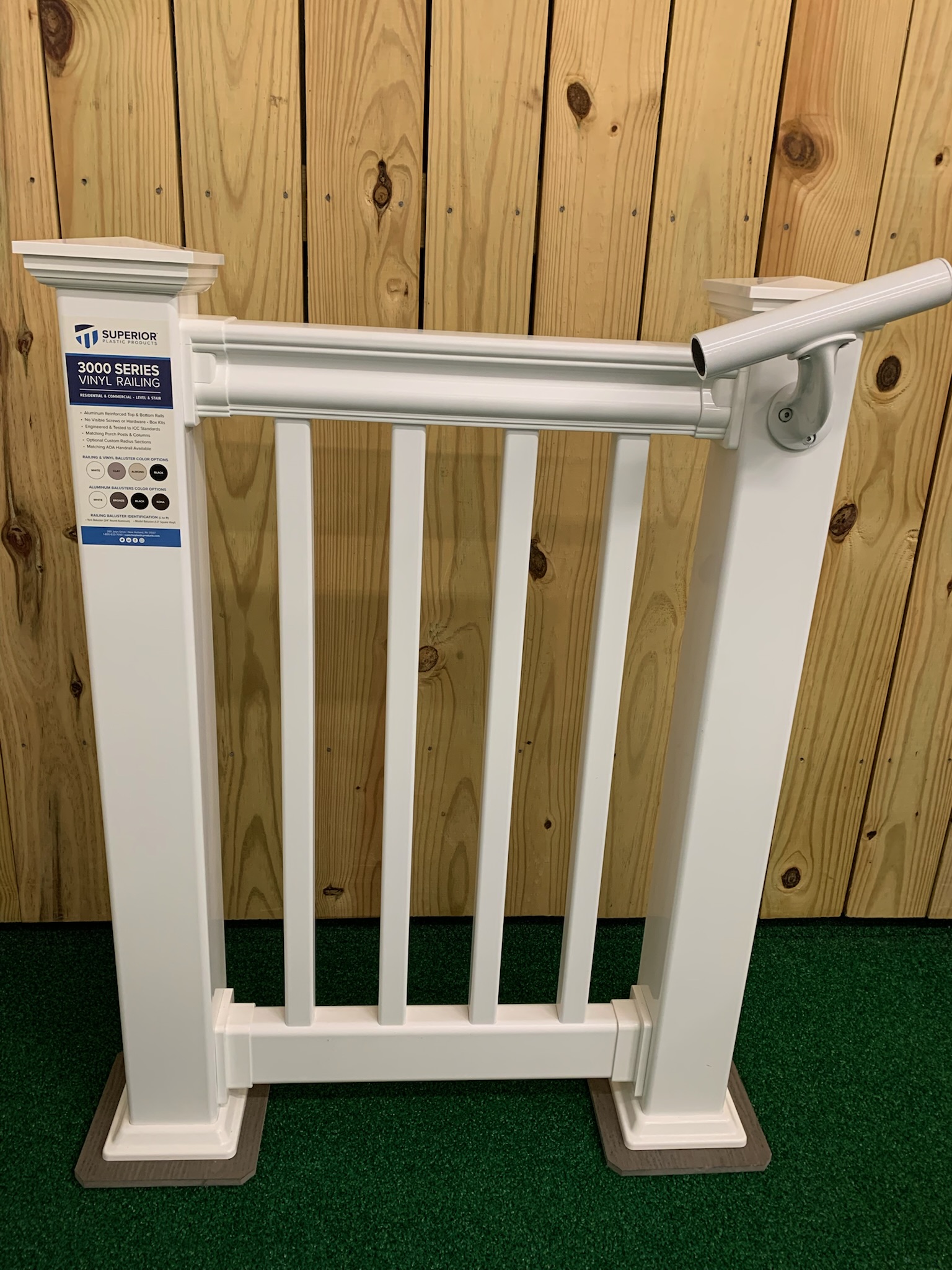 A white, composite fence for a deck featuring a railing for easy stair stepping.