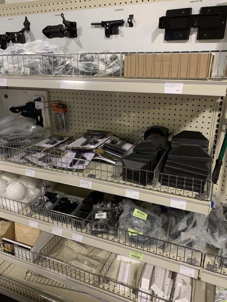 Store shelves stocked with fence and deck accessories and parts, all individually wrapped.