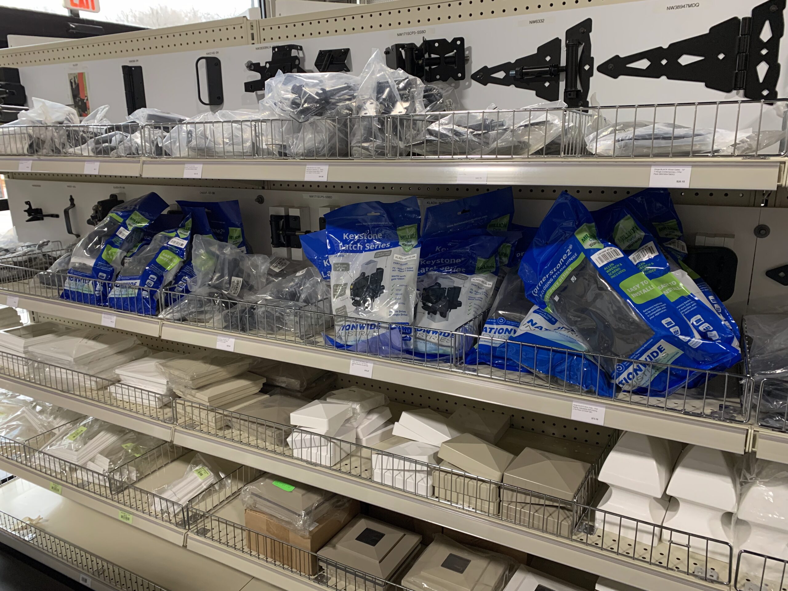 Store shelves stocked with fence and deck accessories and parts, all individually wrapped.