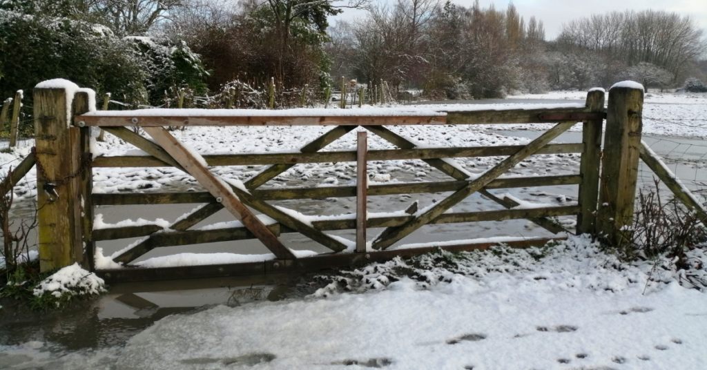 A split rail fence gate covered with snow and ice.