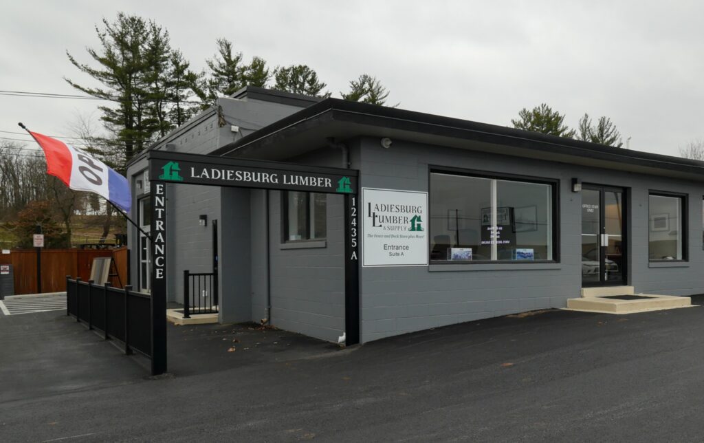 Standing out in front of the Ladiesburg Lumber store, the building is painted gray with black accents around the windows and door.