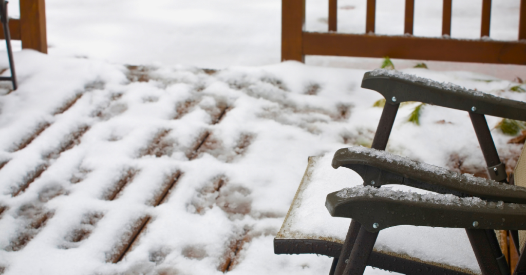 A snow covered back deck with a chair in focus.