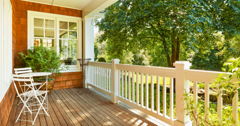 A beautifully designed side porch with white deck railing and matching furniture.