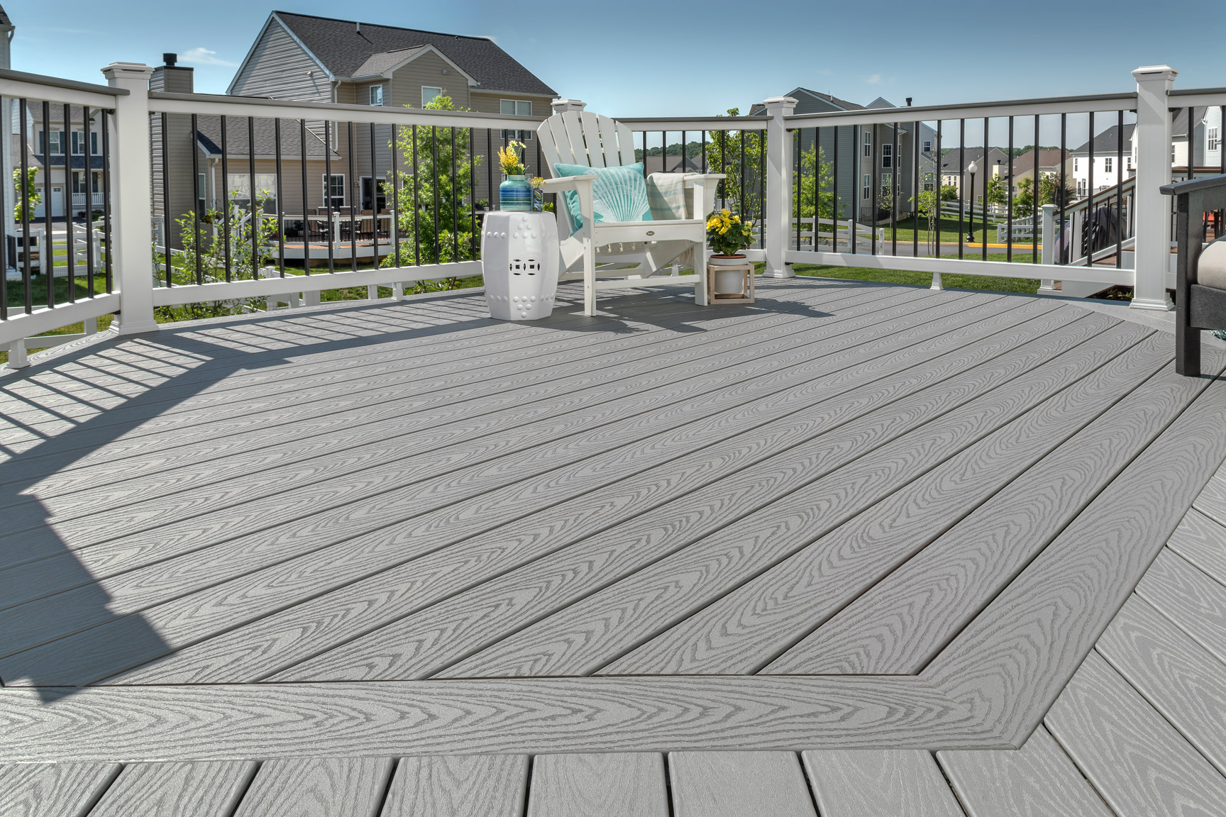A close up shot of gray decking contrasted by a white deck rail with black guard rails.
