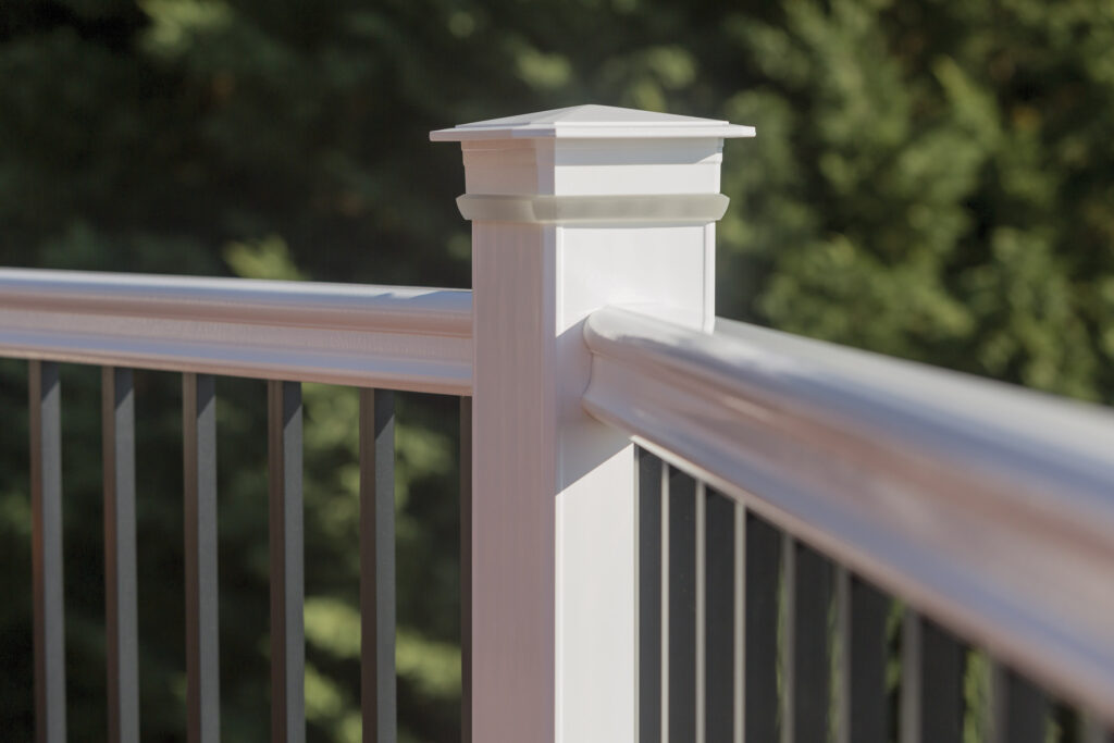 A close up up a white aluminum deck railing white black rod guards.