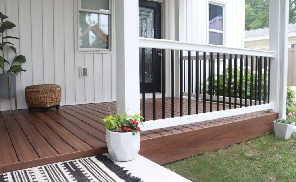 A bold, modern deck featuring a white fence & posts with black bars sitting atop a dark brown deck.