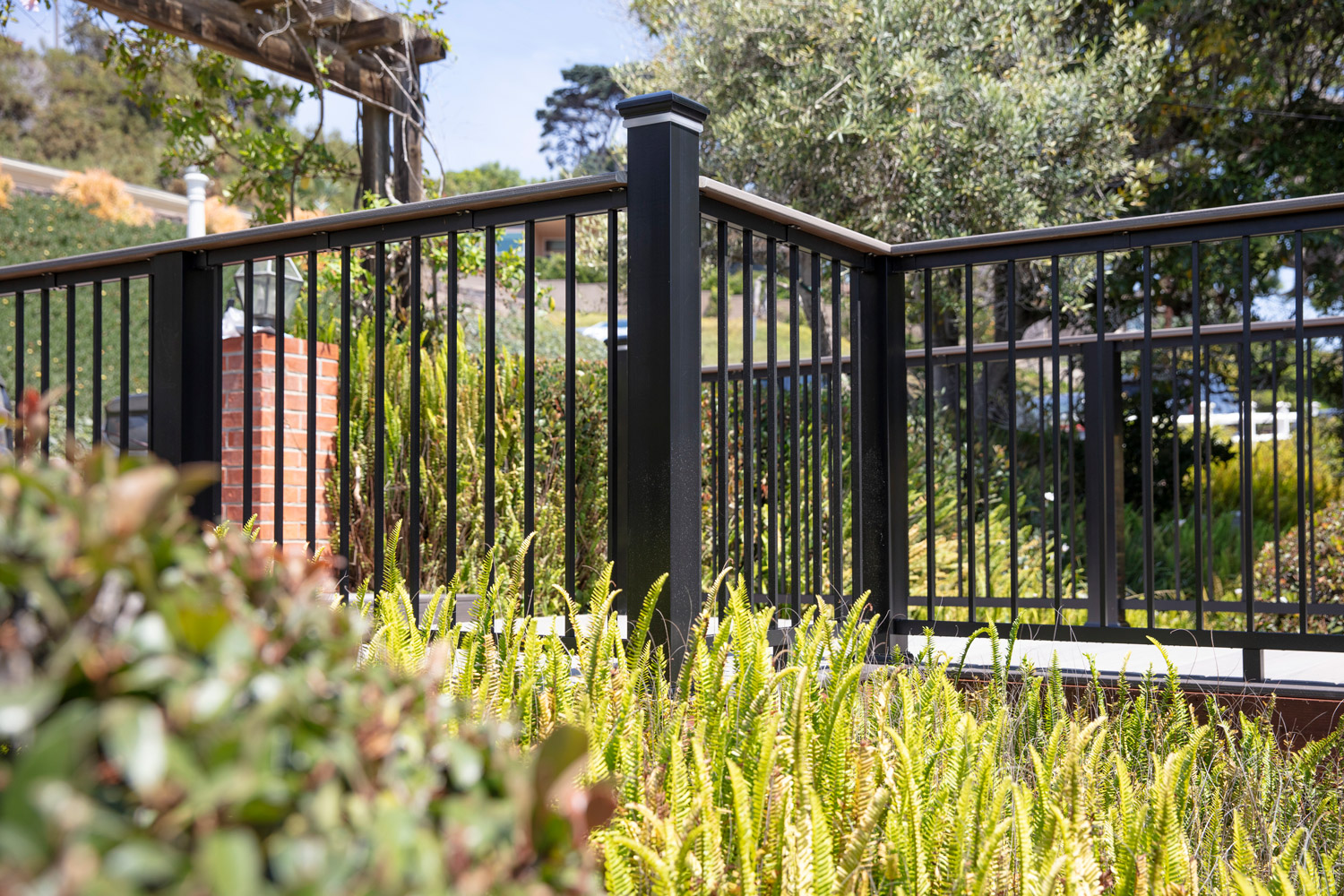 From the ground looking up, a dark black aluminum railing white white accents sits on a sunny day.