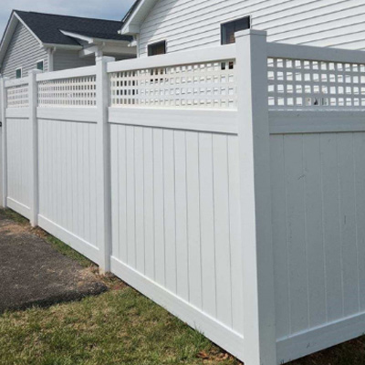 A tall white privacy fence with a checkerboard pattern cutout up top.