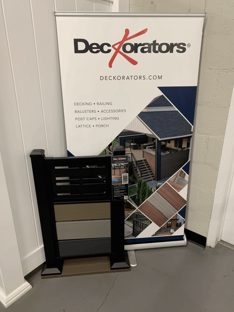 A DecKorators sample deck fence with store poster.