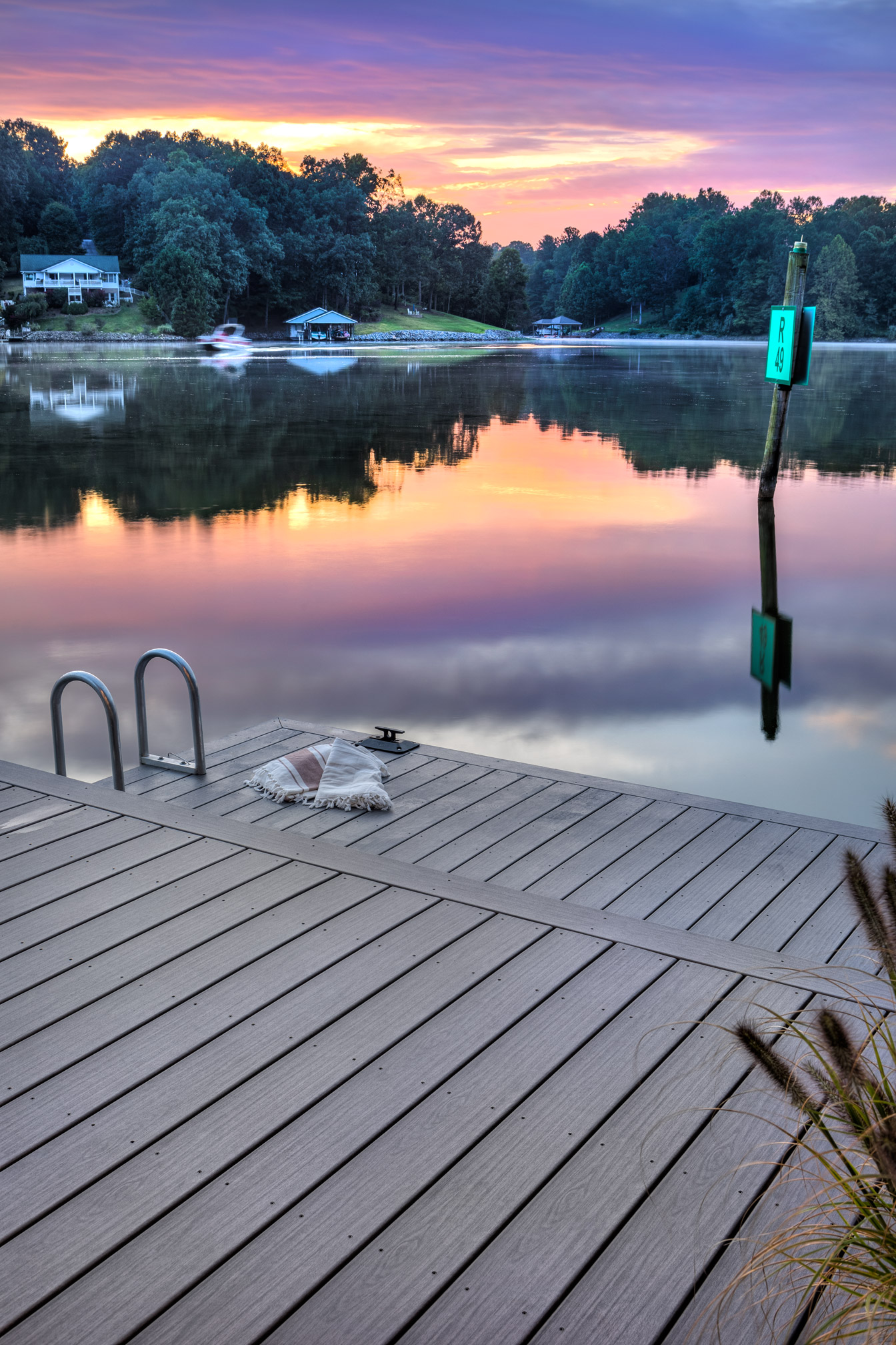 On the deck adjacent to the a lake, there is a ladder into the water off to the left.