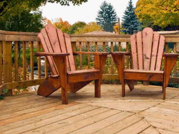 A wood deck with two wood chairs on a fall day