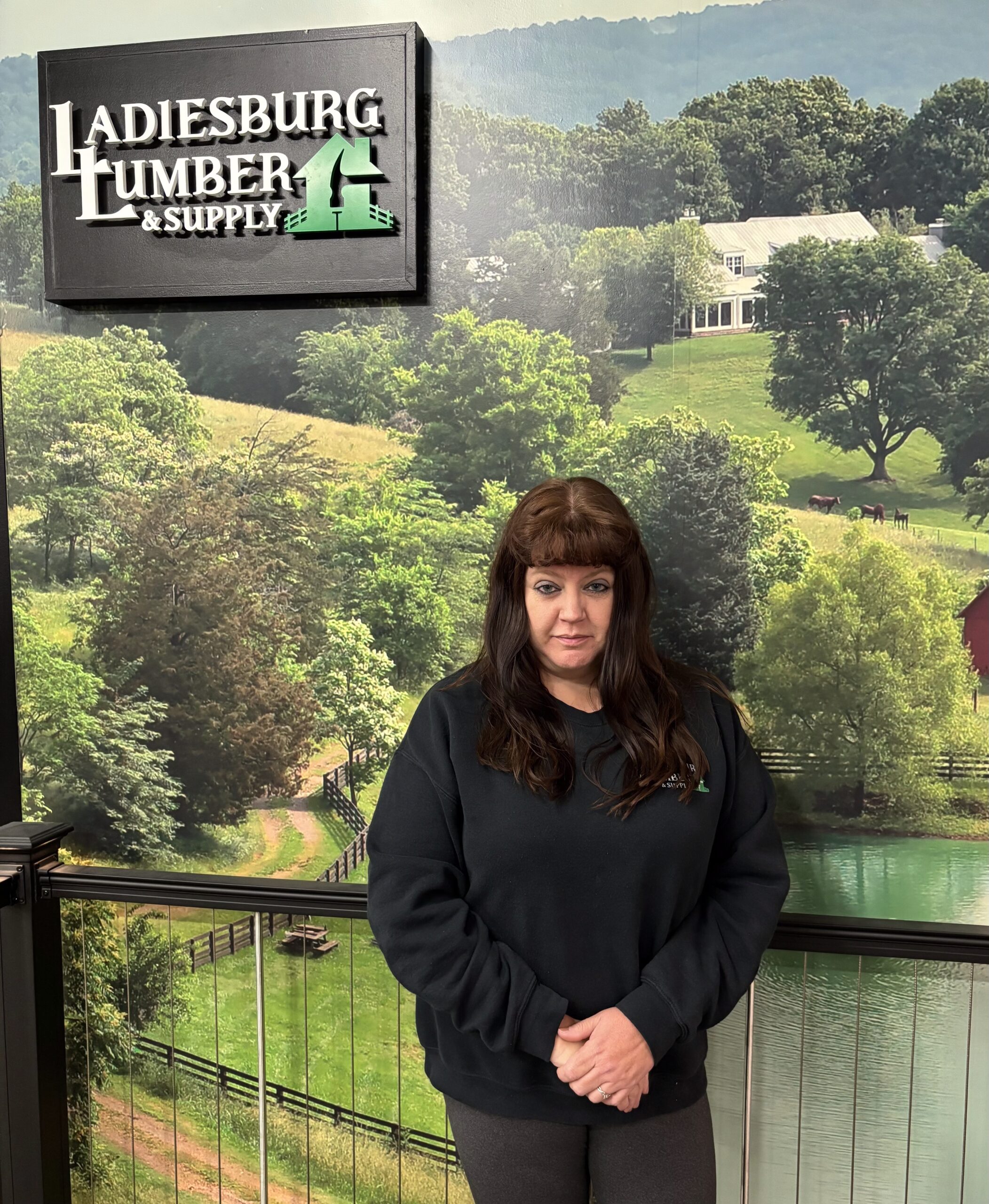 Tricia Walker (Accounting Manager) standing in front an in store branded graphic.