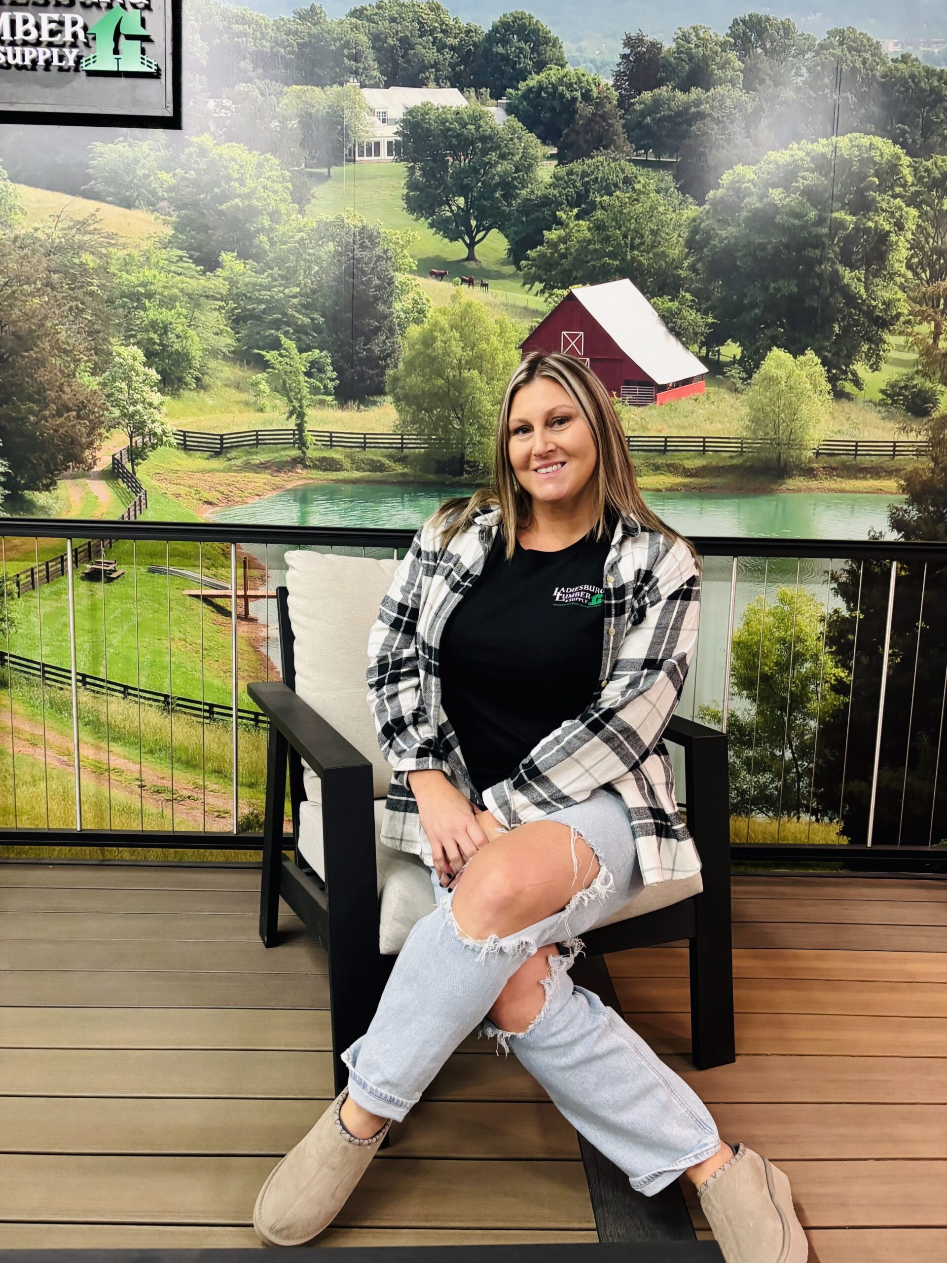 Amanda Talbott (Sales Manager) sitting on a chair in front of a farm graphic in store.