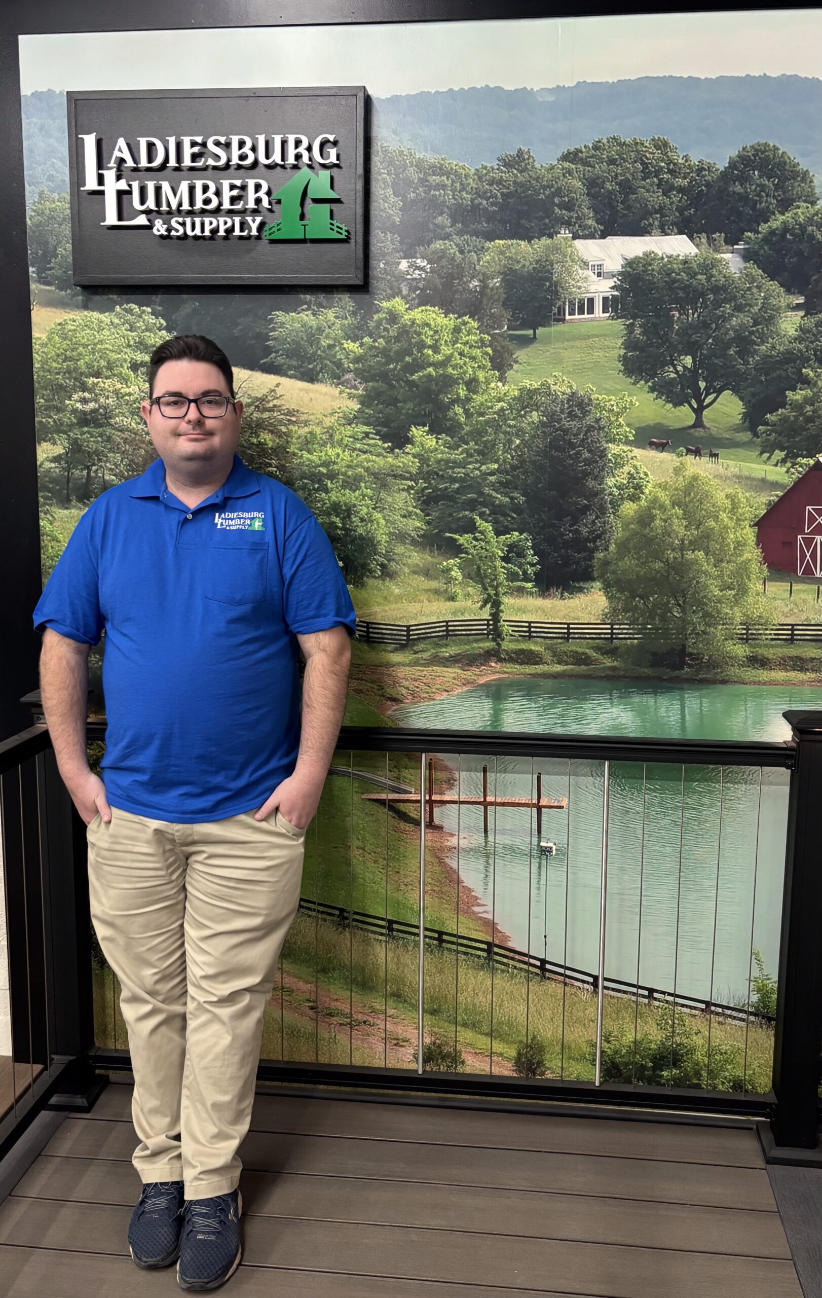 Deven Hartman (Inside/Outside Sales) in a blue, branded polo standing in front of an in store display.