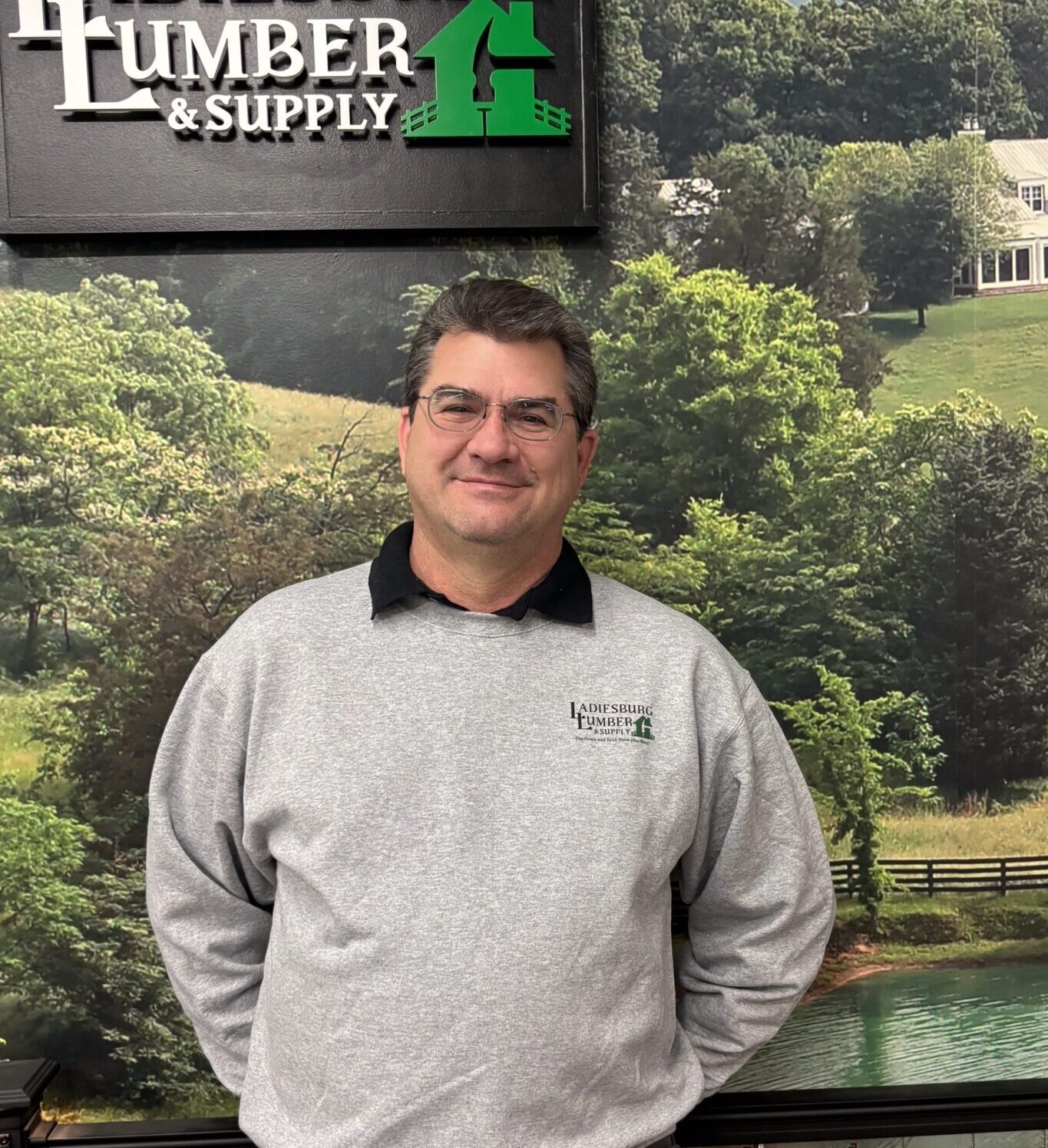 Tom Garst (Benjamin Moore Paint Store Manager) in a gray, branded sweater standing in front of an in store display.