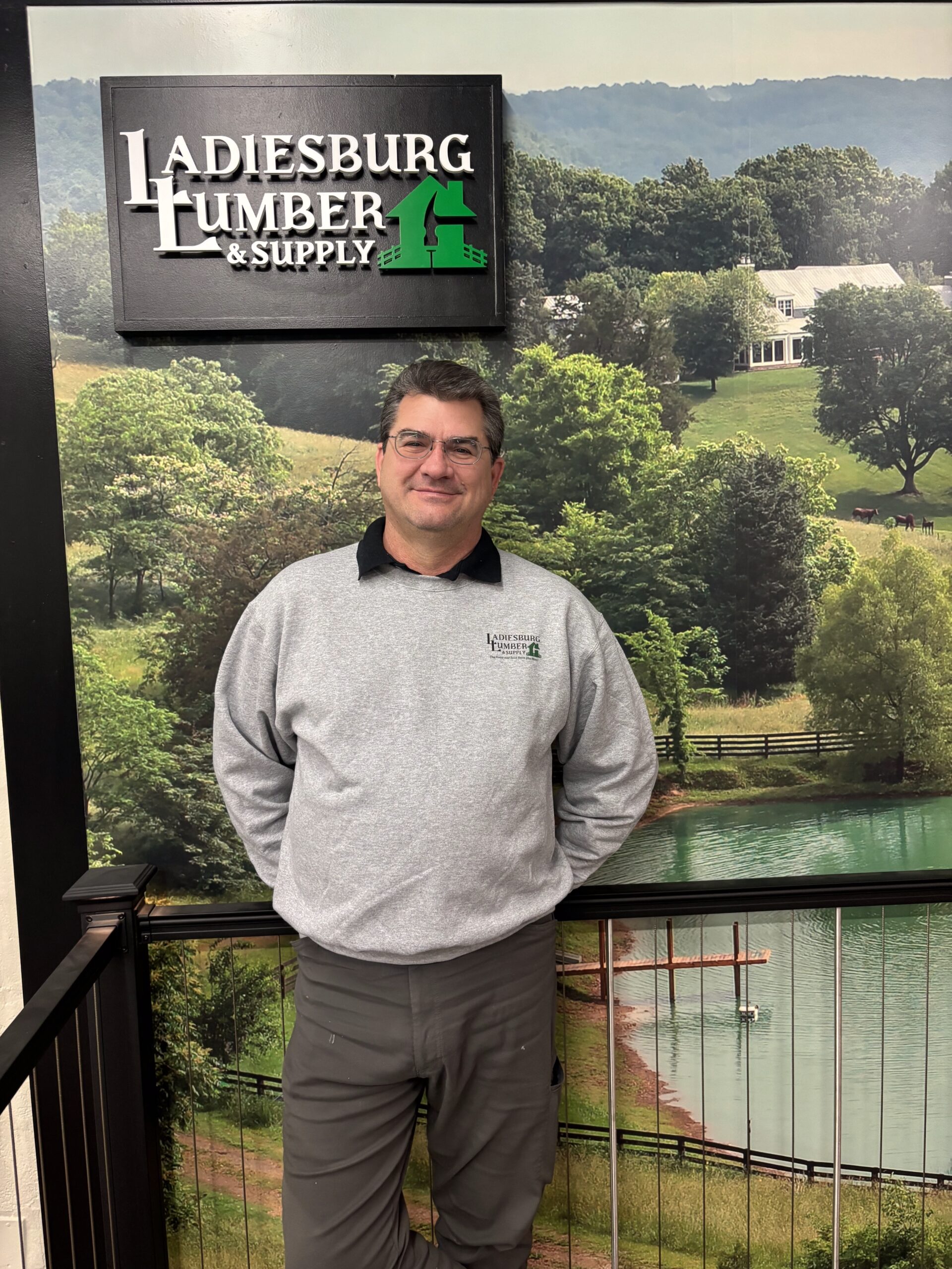 Tom Garst (Benjamin Moore Paint Store Manager) in a gray, branded sweater standing in front of an in store display.