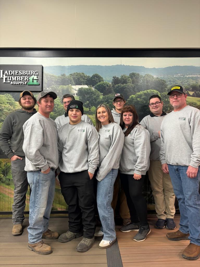 The Ladiesburg Lumber employees in gray, branded sweaters standing in front of an in store display.